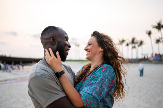 Happy romantic couple kissing on the beach at sunset. Diverse man and woman in love