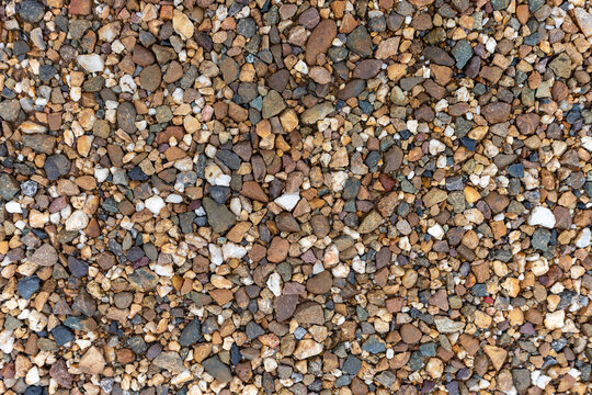Multi-colored small gravel and pebbles tightly packed together forming a rough natural textured surface.