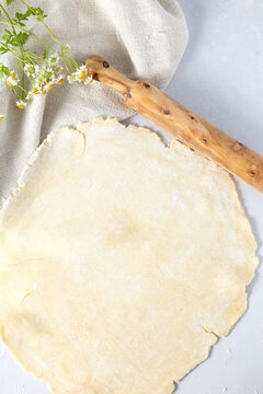 Rolled out pastry dough with rolling pin and flowers
