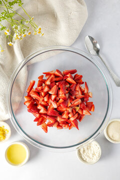 Chopped strawberries in a glass bowl with baking ingredients