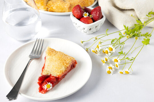 Slice of rustic strawberry galette with chamomile flowers
