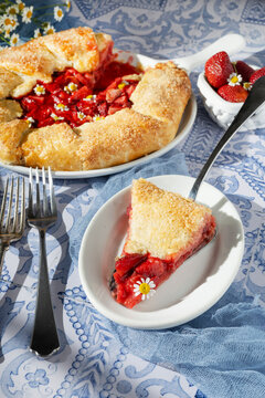 Slice of rustic strawberry galette on blue tile