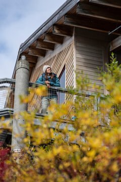 Woman in a beanie smiling on a tram house balcony at a resort
