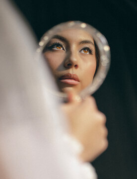 Young woman looks up at her reflection in a mirror