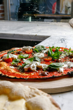 Artisan pizza with burrata and olives on a pizzeria table