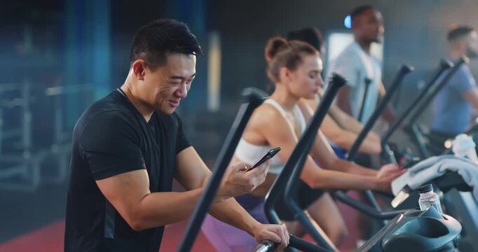 Fitness enthusiasts work out at a modern gym, tracking their progress on their phones