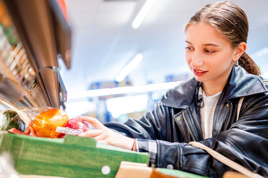 Girl Shopping In Supermarket Chooses Pepper