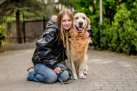Happy Teen Girl Sitting With A Golden Retriever On A Walk