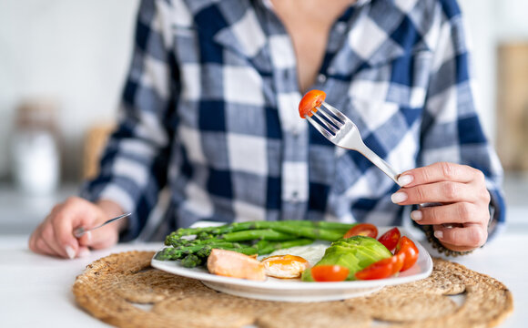 Girl Eating A Breakfast Of Egg, Fish, Asparagus, And Cherry Tomatoes, Healthy Eating