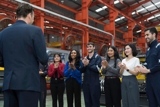 Group of male and female workers and manager standing discussing, meeting together in factory. Diverse corporate colleagues and multicultural in factory