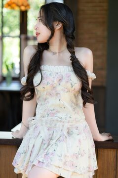 Young woman with long braided hair in floral dress enjoying relaxed indoor moment