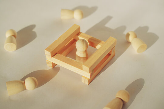 Wooden peg dolls inside a small square enclosure of blocks