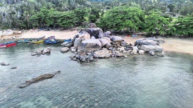 Aerial Drone View of Turun Aban Beach with Granite Boulders, Traditional Fishing Boats and Crystal Clear Tropical Water in Bangka Island Indonesia