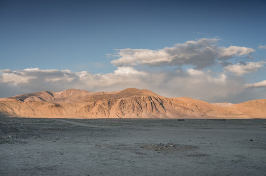 Evening panoramic view of a mountain landscape at sunset in the Pamirs in Tajikistan, with the mountain range illuminated by the setting sun