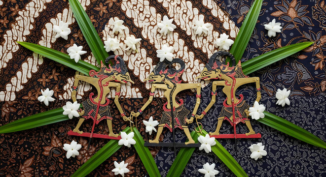 Traditional Indonesian Wayang Kulit Puppets on Batik Fabric with Jasmine Flowers and Pandan Leaves