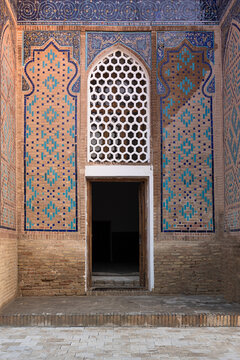 Decorated entrance of a mausoleum at Shah-i-Zinda necropolis in Samarkand featuring intricate brickwork and turquoise tilework. Ideal for travel publications and architectural studies.