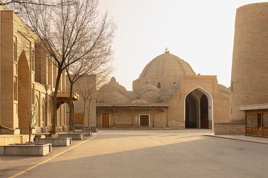 Toqi Zargaron trading dome in Bukhara with pointed archway and brick facades on an empty square at dawn. Historic Central Asian architecture ideal for travel and heritage publications.