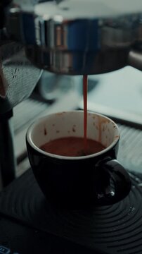 4K Pouring coffee stream from professional machine in cup. Barista man making double espresso, using filter holder. Flowing fresh ground coffee. Drinking roasted black coffee in the morning.	

