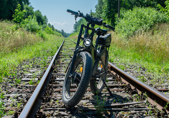 Fototapeta premium Front view of an electric mountain bike with thick fat tires parked on an old abandoned railway track 