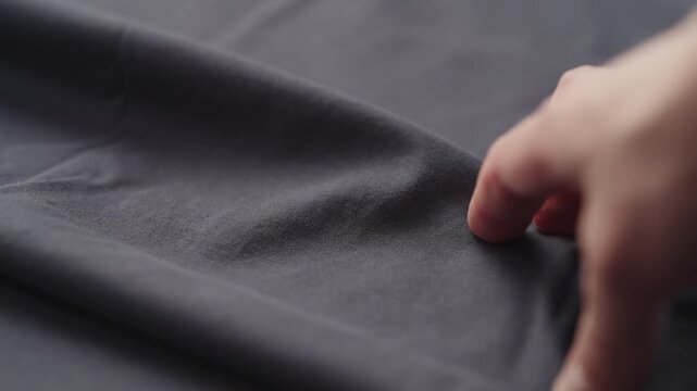 Slow motion man hand checking blue cotton jersey cloth