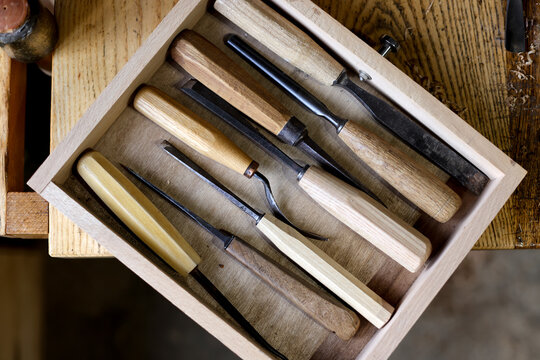 Traditional woodturning tools arranged in a wooden drawer in an artisan workshop