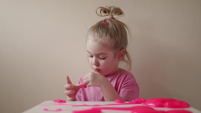 Toddler explores pink slime in a playful indoor setting on a sunny afternoon