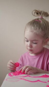 Toddler explores pink slime in a playful indoor setting on a sunny afternoon