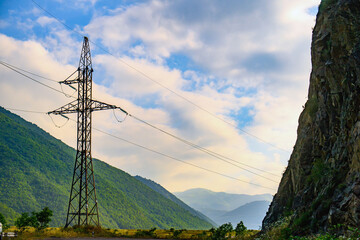 Obraz premium High voltage transmission tower near mountainous terrain