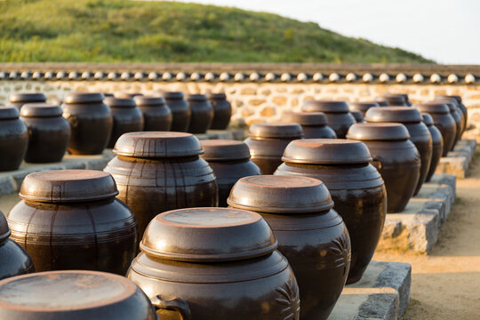 Rows of traditional Korean onggi jars on a stone platform at sunrise