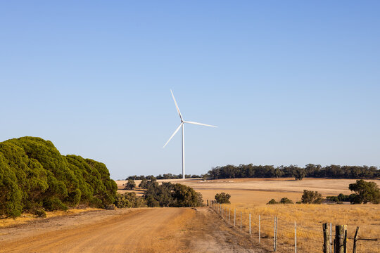 Wind turbine rising above countryside dirt road