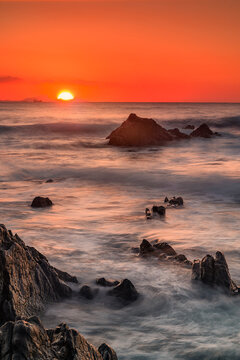 Long exposure seascape at Barrika Beach with dramatic rock formations, misty waves and colorful sunset clouds over the Cantabrian coast