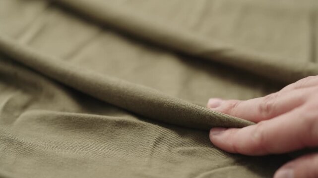 Slow motion man hand checking green cotton jersey cloth