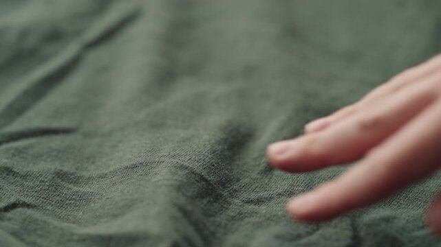 Slow motion man hand checking green linen jersey cloth