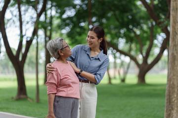 Fototapeta premium Young woman and senior woman walking together in a green park during daytime