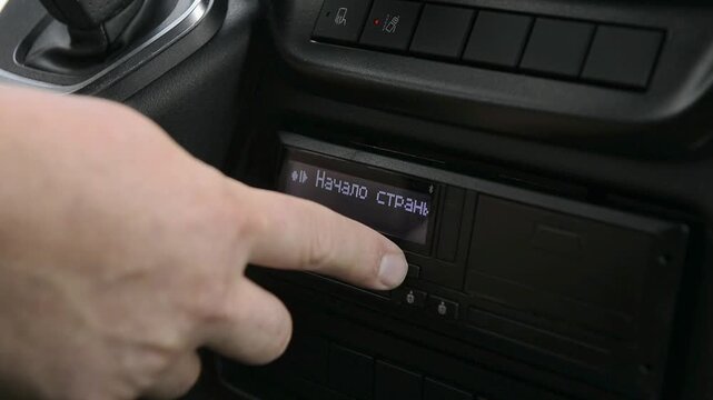 Truck driver entering work data on tachograph device