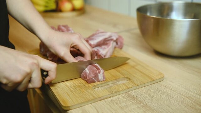 Cutting raw meat into equal portions on wooden board