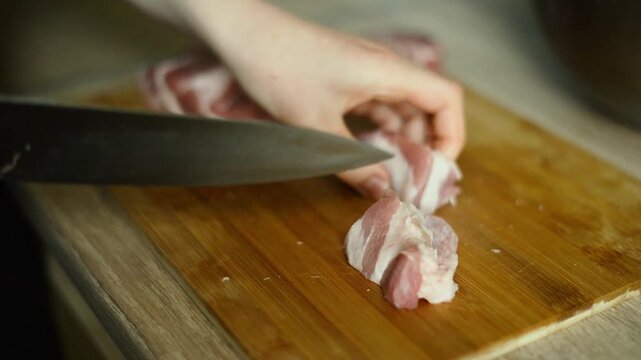 Chopping raw meat into small cubes on cutting board