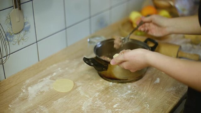Placing minced meat filling on dough circle with fork