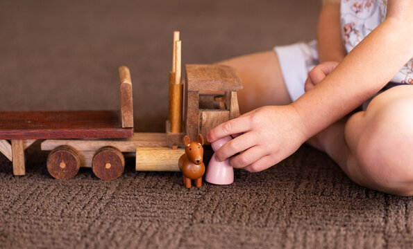 Child playing with dog and toy person by flatbed truck on brown floor