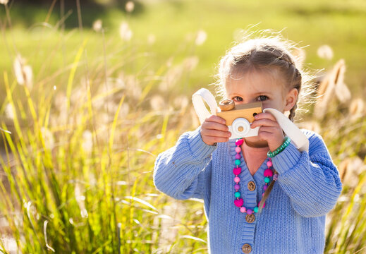 Child playing with toy wooden camera pretending to be a photographer