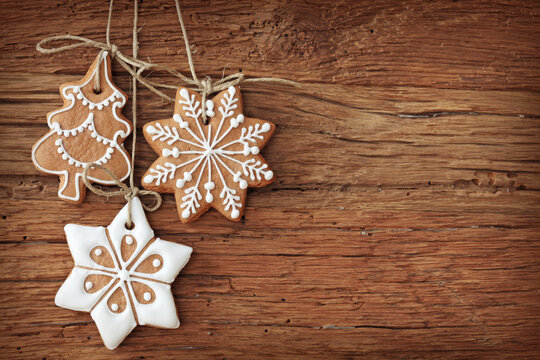 Set of three gingerbread cookies hanging as christmas ornaments on weathered wooden background with gingerbread