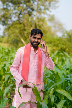 Indian farmer talking on mobile phone at corn agriculture field