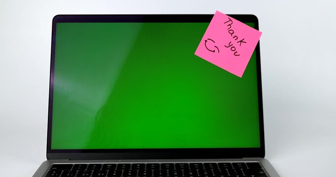 Laptop with green screen and pink Thank you sticky note, chroma key