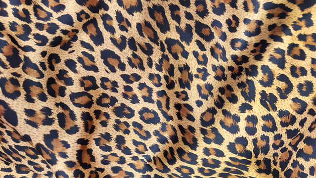 Close up of leopard print fabric with realistic african animal pattern and soft folds. Fashion textile background featuring a wild feline design for clothing, upholstery, accessories, and decor.