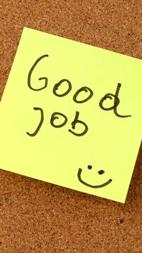 A yellow sticky note with the message Good Job is placed onto a cork bulletin board, highlighting appreciation, motivation, recognition, teamwork, and positive communication in an organized workspace.