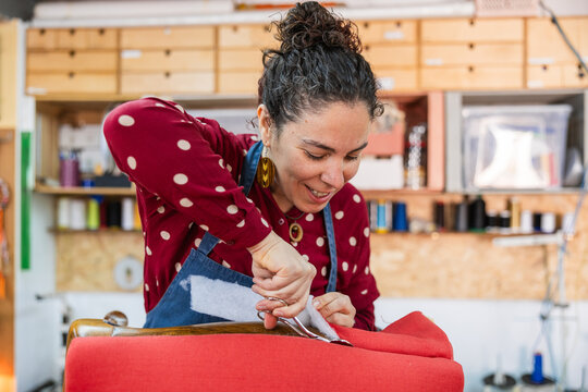 Woman upholsterer cutting fabric managing small business