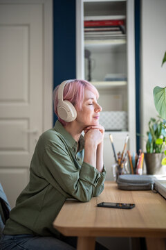 Pleased positive woman listening music playlist online on smartphone streaming app in wireless headphones, smiling tranquil female relaxing and dreaming while enjoying favorite songs on mobile.