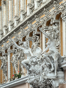 Baroque palace facade with classical white sculptures and columns, ornate architecture detail