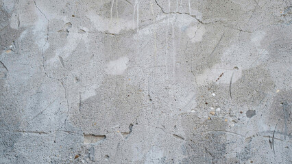 Fototapeta premium Weathered gray concrete wall surface with fine cracks, stains, and rough texture, close-up view of industrial building exterior