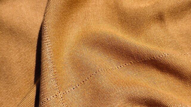 Background view of a camel brown knit fabric texture featuring intricate pointelle seam detail, elegant drapery folds, and fine woven geometric pattern, ideal for autumnal fashion designs.